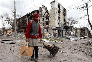 Ukrainerin vor einem zerstörten Wohnhaus in Mariupol