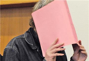 Der wegen dreifachen Kindermordes angeklagte Martin N. verdeckt am Montag (27.02.2012) im Landgericht in Stade vor der Urteilsverkündung im Prozess gegen ihn sein Gesicht hinter einem Aktendeckel.