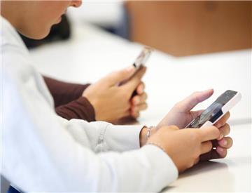 Schülerinnen benutzen ihr Smartphone im Unterricht.  Medienpädagogen fordern: Schulen sollten Smartphones sinnvoll einbinden statt verbieten.
