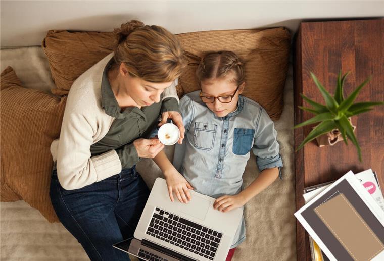 Frau und Mädchen auf Bett mit Laptop