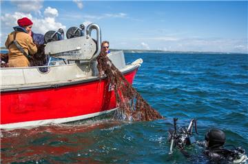 Meeresbiologin Gabriele Dederer zieht gemeinsam mit Fischern von Tauchern gesicherte Geisternetze aus der Ostsee an Bord des Fischkutters "Ecke20".