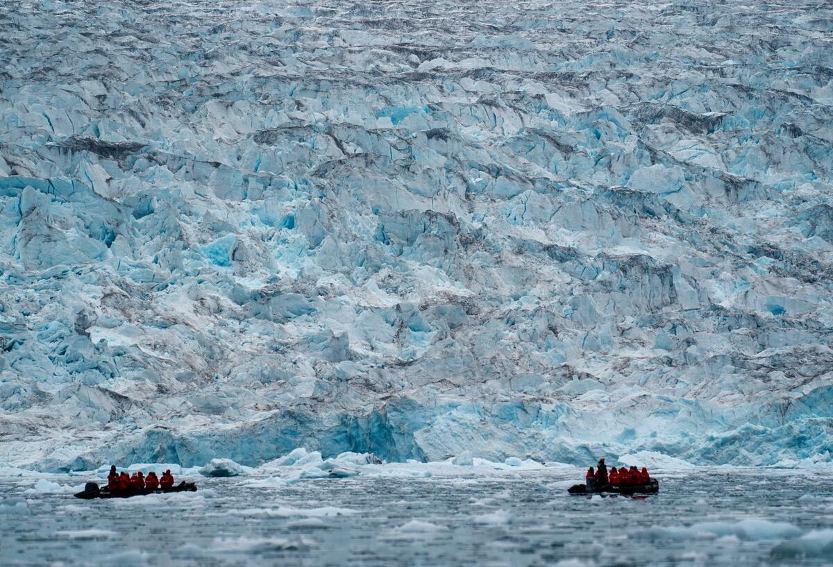 Zwei Gruppen von Poseidon Expeditions betrachten einen Gletscher, der auf der Wasserlinie im Scoresby Sund liegt. 