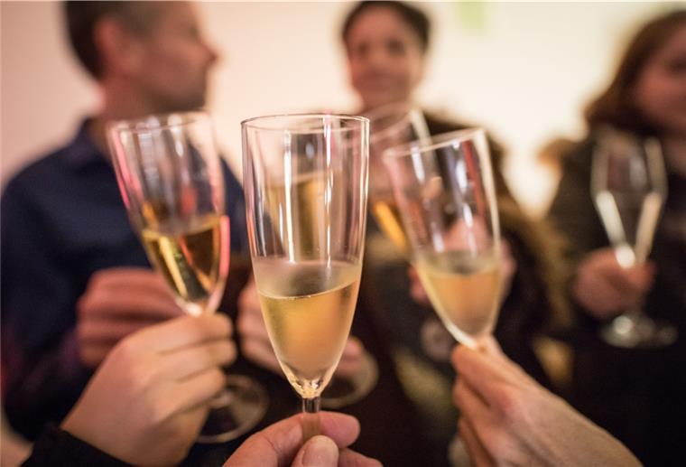 Personen stoßen mit Sekt an.