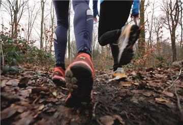 Zwei junge Frauen laufen im Winter im Wald. Joggen in der kalten Jahreszeit, mit waermender, Wind- und Wasserdichter Funktionsbekleidung.