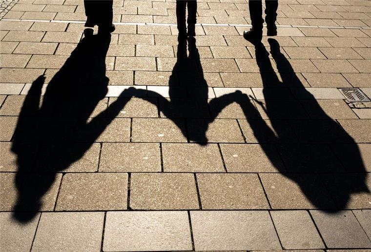 Neue Kindergeld-Regelung: Weniger Bürokratie für Eltern Die Schatten von zwei Erwachsenen und einem Kind fallen in den Morgenstunden auf den Asphalt. Das Kindergeld wird erhöht.
