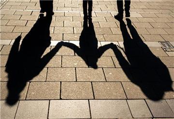 Die Schatten von zwei Erwachsenen und einem Kind fallen in den Morgenstunden auf den Asphalt. Das Kindergeld wird erhöht.