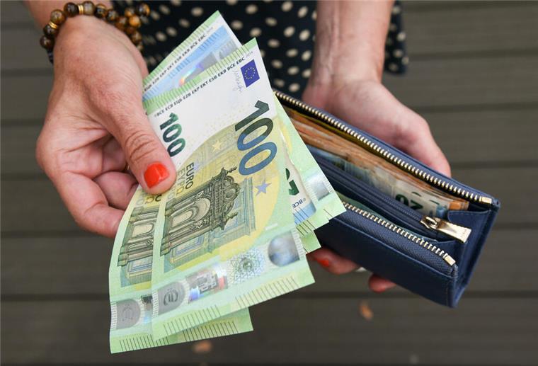 Eine Frau hält eine mit mehreren Geldscheinen gefüllte Geldbörse in einer Hand, darunter Hundert-, Fünfzig- und Zwanzig-Euro-Scheine, und einige Geldscheine in der anderen Hand. Ein Plan der Merz-Regierung soll dafür sorgen, dass am Ende mehr Netto-Lohn bleibt.