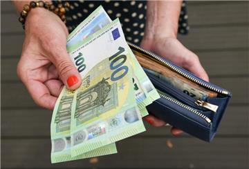 Eine Frau hält eine mit mehreren Geldscheinen gefüllte Geldbörse in einer Hand, darunter Hundert-, Fünfzig- und Zwanzig-Euro-Scheine, und einige Geldscheine in der anderen Hand. Ein Plan der Merz-Regierung soll dafür sorgen, dass am Ende mehr Netto-Lohn bleibt.