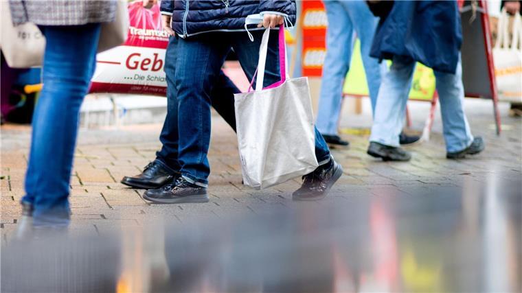 Menschen gehen am verkaufsoffenen Sonntag mit Einkaufstaschen durch die Fußgängerzone der Innenstadt.