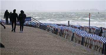 Menschen gehen bei stürmischen Wetter an der Nordsee entlang.