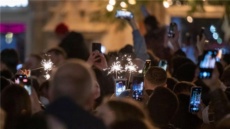 Menschen machen Fotos mit ihren Smartphones, während sie den Jahreswechsel feiern.