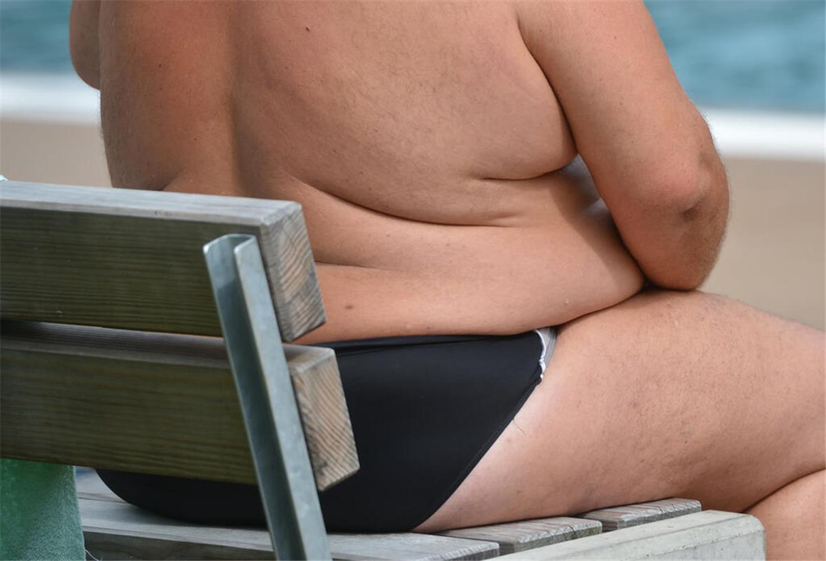 Schneller abnehmen: Neuer Wirkstoff macht Menschen mit Übergewicht Hoffnung Ein übergewichtiger Mann sitzt in einem Freibad.