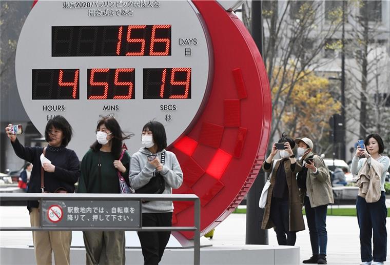 IOC und Japans Premier sprechen von Olympia-Verschiebung Menschen mit Mundschutz machen ein Selfie vor der offiziellen Countdown-Uhr für Olympia in Tokio 2020. Die Spiele könnten verschoben werden.