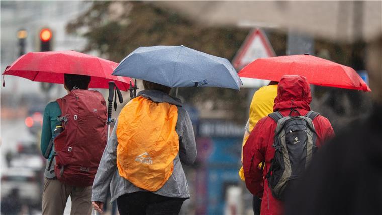 Neue Woche bringt Wolken: Regen wahrscheinlich ab Dienstag Menschen schützen sich bei Regen mit ihren Schirmen.