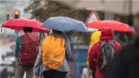 Menschen schützen sich bei Regen mit ihren Schirmen.