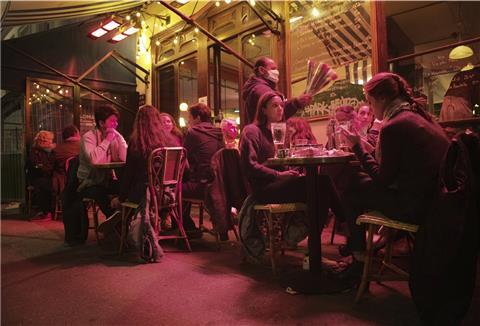 Menschen im Außenbereich eines Cafés bei Nacht.