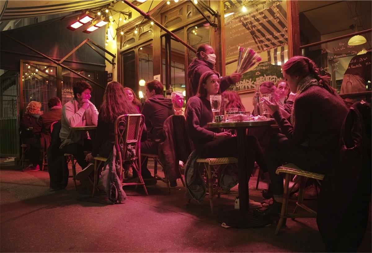 Menschen im Außenbereich eines Cafés bei Nacht.
