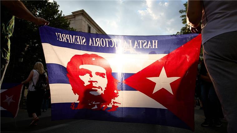 Menschen tragen eine Fahne mit einer Abbildung des legendären Ernesto Che Guevara während einer Kundgebung zur Unterstützung der kubanischen Regierung.