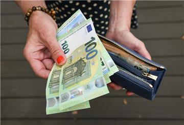 Eine Frau hält mehrere Geldscheine und eine Geldbörse in der Hand. Menschen zu pflegen, kostet Geld. Mit einem Kombi-Zuschuss können Betroffene finanzielle Entlastung bekommen.