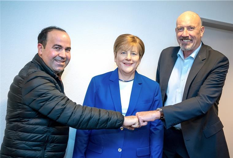 „Mutti“ Merkel zieht in Bremen ein zwei Männer mit der Wachsfigur von Frau Merkel.
