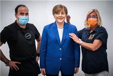 Zwei Personen neben einer Wachsfigur der Bundeskanzlerin.