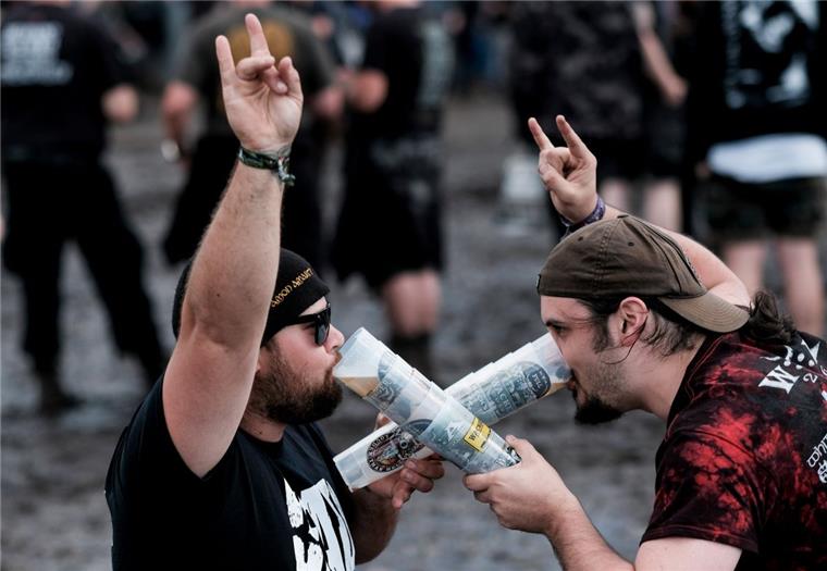 Metal-Fans feiern in Wacken (Schleswig-Holstein) auf dem mit Schlamm überzogenen Festivalgelände des Wacken Open Air vor den Bühnen.