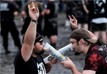 Metal-Fans feiern in Wacken (Schleswig-Holstein) auf dem mit Schlamm überzogenen Festivalgelände des Wacken Open Air vor den Bühnen.