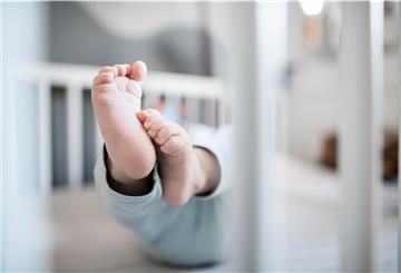 Die Füße eines Babys sind in einem Kinderbett zu sehen.