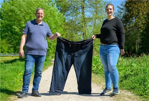Michael Wirtz (l) und Meike Preußner halten eine Hose in Größe 60 in den Händen. Beide engagieren sich in der Adipositas-Selbsthilfe und haben in der Vergangenheit rund 160 Kilogramm auf die Waage gebracht.