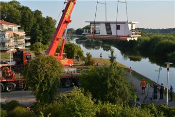 Millimeter für Millimeter wird das erste Hausboot für die "Marina am See" in Bad Bederkesa auf den Hadelner Kanal heruntergelassen.