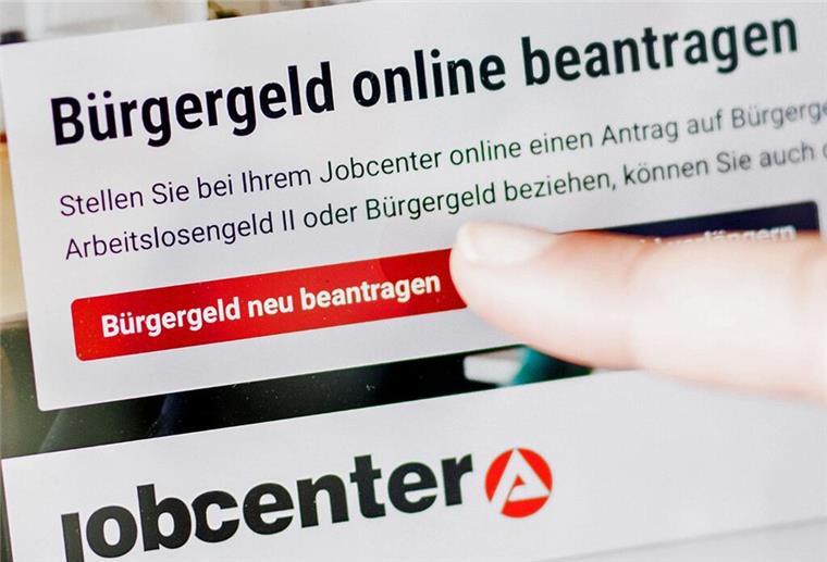 Eine Frau tippt auf einem Tablet auf einen Link zum Beantragen des Bürgergeldes im Kundenbereich im Jobcenter Berlin Mitte.