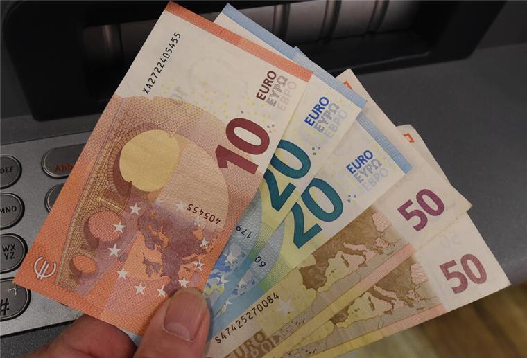 Bis zu 370 Euro! Dieser Zuschuss für Millionen Haushalte kommt im September Eine Person hält Geldscheine vor einem Geldautomaten in die Kamera. Millionen Bürger bekommen im September einen Zuschuss.
