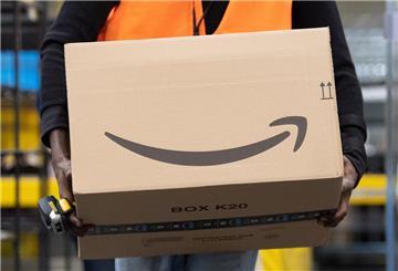 Ein Sortiermitarbeiter von Amazon trägt in einem Verzeilzentrum ein Paket. Millionen Kunden von Amazon müssen aktuell vorsichtig sein: Sie stehen im Fokus von Betrügern, die sensible Daten klauen wollen.