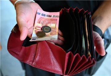Ein Kellner eines Restaurants hält einen Geldbeutel in der Hand, während er in der anderen Hand Geld hält. Minijobber dürfen ab 2026 rund 50 Euro mehr im Monat verdienen – rund 603 Euro. Ein Jahr später steigt die Grenze erneut.