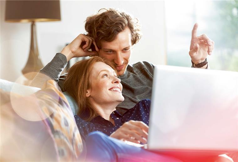 Paar sitzt mit Laptop auf dem Sofa und plant seine Zukunft