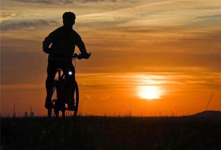 Feierabend-Fahrradtour startet in Bremerhaven Ein Mann fährt mit einem Fahrrad kurz nach Sonnenaufgang über einen Feldweg
