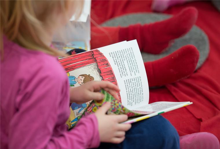 Ein kleines Mädchen liest in einem Buch.