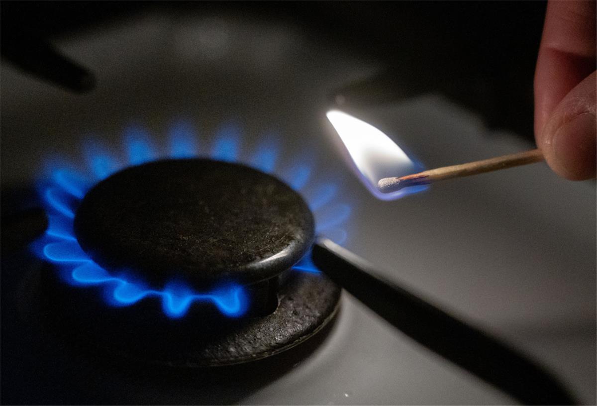 Eine Gasflamme wird auf einem Küchenherd mit einem Streichholz entzündet.