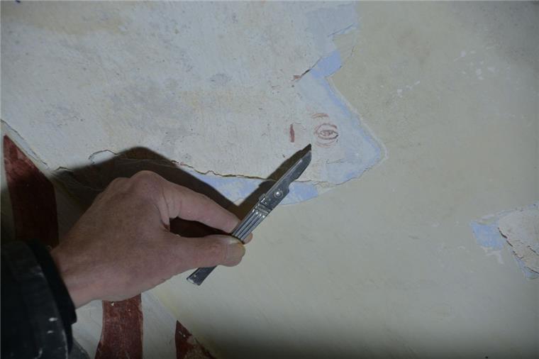 Mit dem Skalpell wird Schicht um Schicht alter Farbe und alten Putzes abgetragen und so die Fragmente der Malereien in Ringstedt freigelegt.