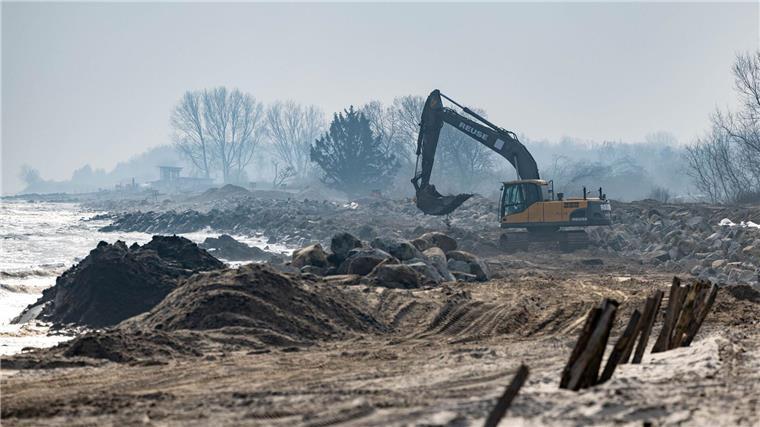 Mit einem Bagger werden große Steine am Strand am Hafen von Damp verladen.
