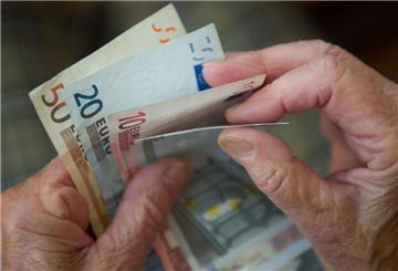Eine Person zählt mehrere Euroscheine. 