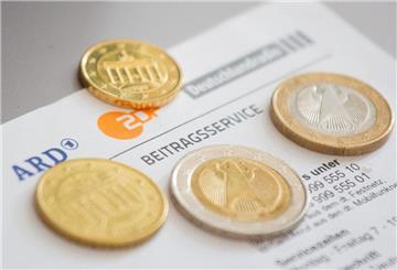 Mehrere Geldmünzen liegen auf einem Brief vom Beitragsservice. Mit einem einfachen Antrag kann man sich vom Rundfunkbeitrag befreien.