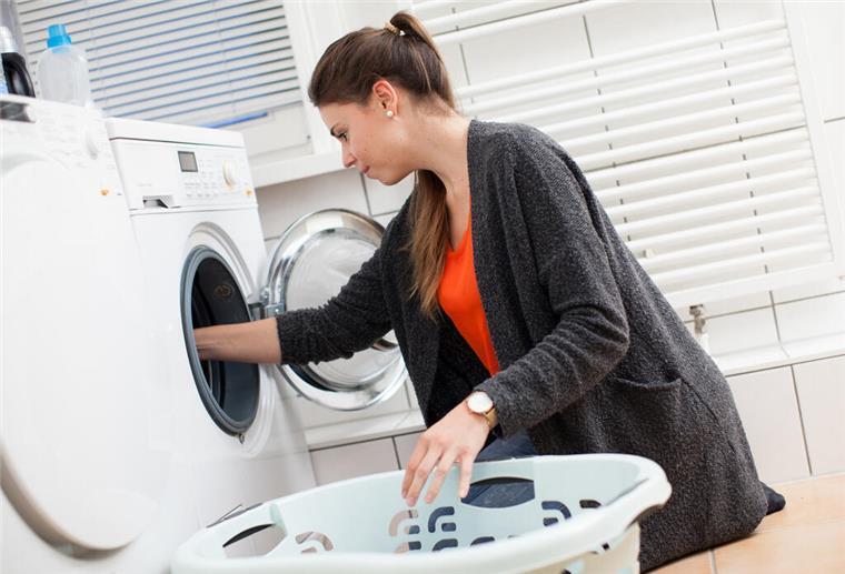 Eine Frau holt Wäsche aus der Waschmaschine. Mit einem simplen Trick lassen sich bei der Waschmaschine viele Euro sparen.