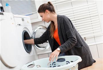 Eine Frau holt Wäsche aus der Waschmaschine. Mit einem simplen Trick lassen sich bei der Waschmaschine viele Euro sparen.
