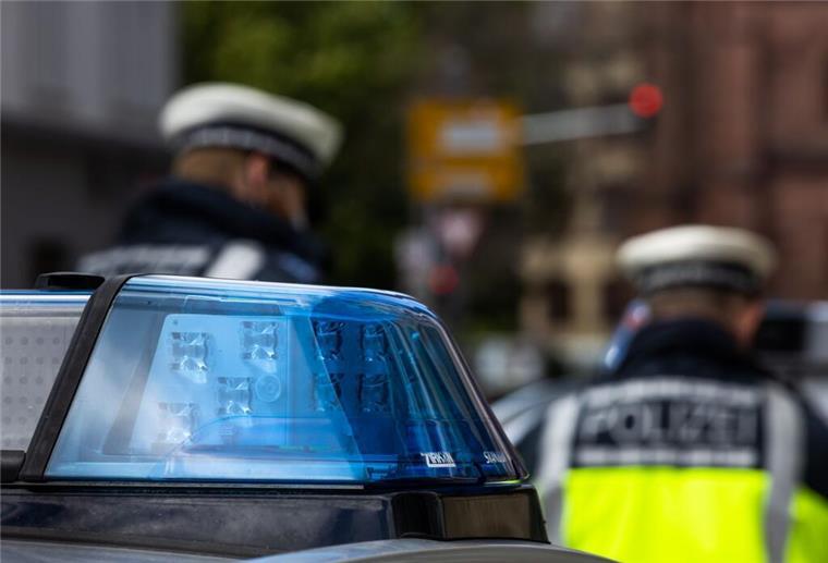 Zwei Polizeibeamte stehen zwischen zwei Einsatzfahrzeugen der Polizei.