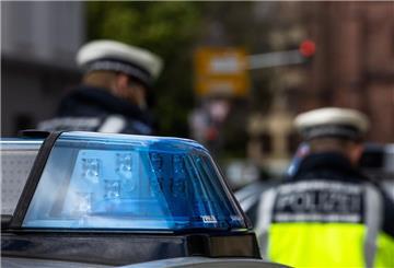 Zwei Polizeibeamte stehen zwischen zwei Einsatzfahrzeugen der Polizei.