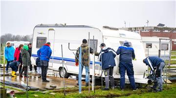 Mit gegenseitiger Unterstützung schieben die Urlauber ihre Wohnwagen auf die Parzellen.
