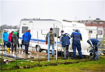 Mit gegenseitiger Unterstützung schieben die Urlauber ihre Wohnwagen auf die Parzellen.