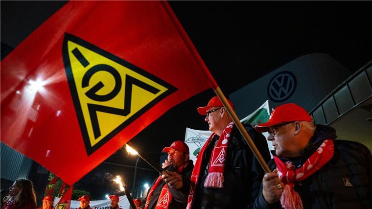 Mit Gewerkschafts-Fahnen stehen Mitarbeiter vor dem Volkswagen-Werk.