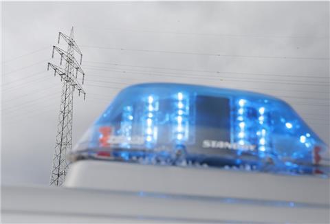 Ein Polizeiauto mit Blaulicht steht vor einem Strommast.